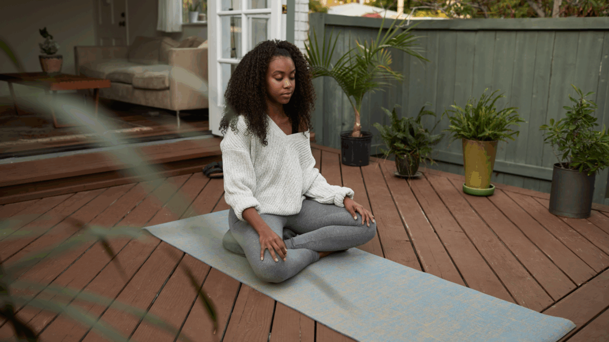 woman unwinding through meditation on her patio as she enjoys a peaceful, relaxing evening outdoors.  