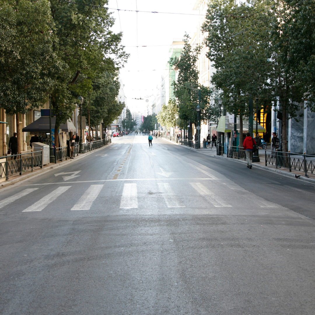 Wide city cross-walk with people walking along the sidewalks on both sides of the road.